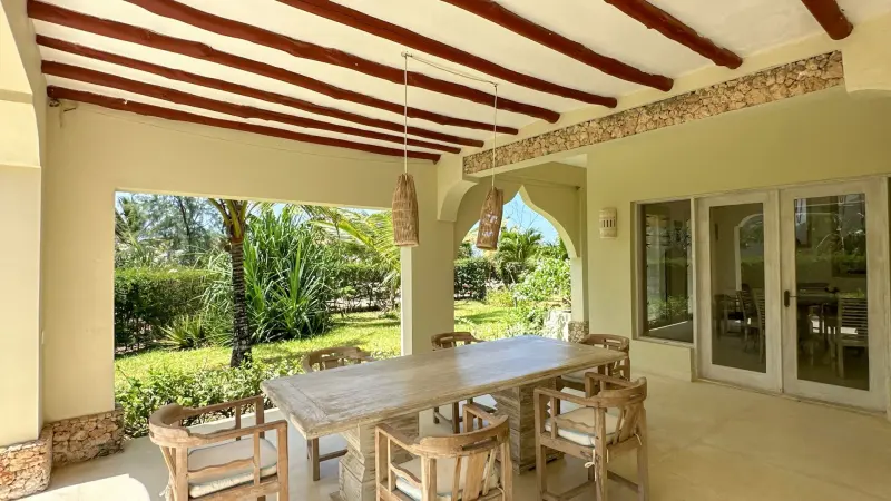 A shaded veranda with a dining table looking out over the garden