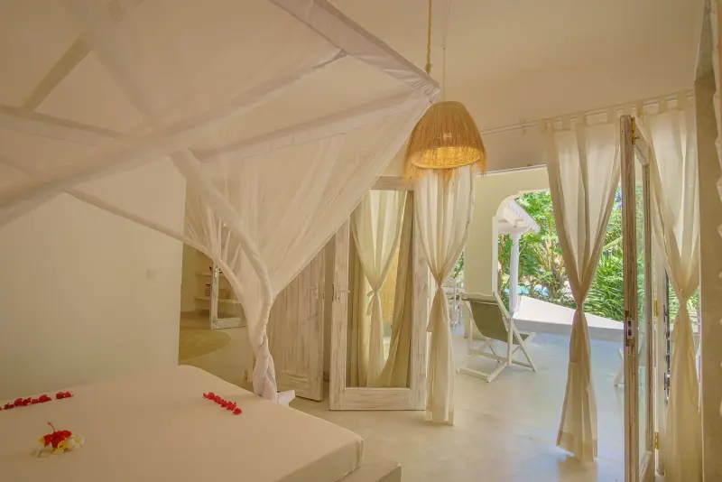 A bedroom with a net-draped bed by the garden doors