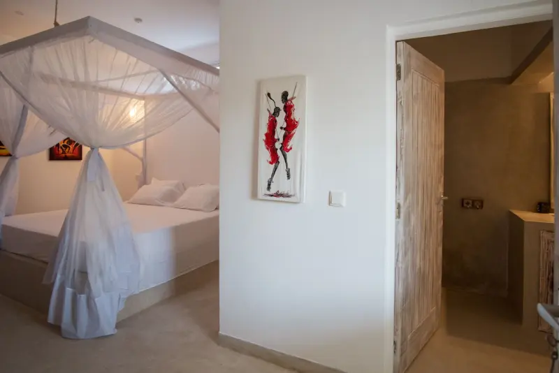 A bedroom with a mosquito net and carved door
