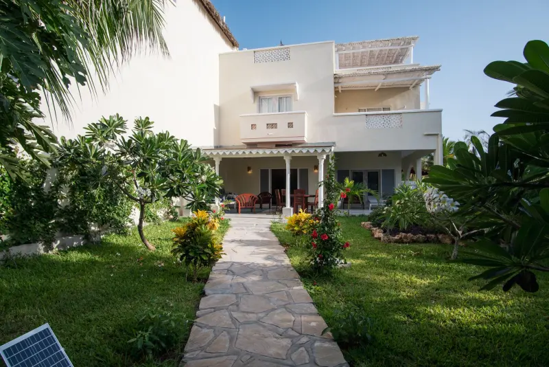 A stone path through the lawn to a white villa