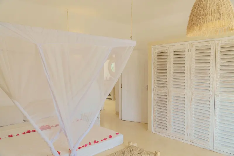 A bedroom with a mosquito net and white shutters